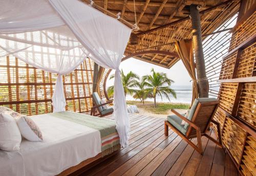 a bedroom with a bed and two chairs on a deck at Playa Viva in Juluchuca