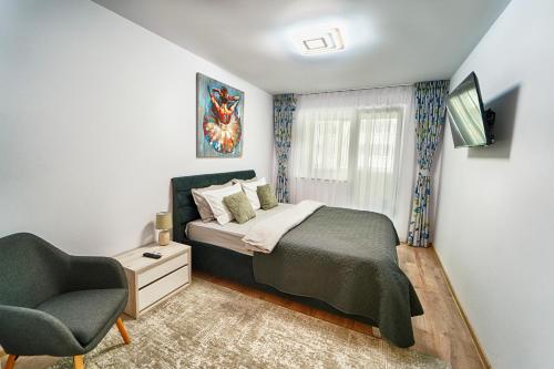 a bedroom with a bed and a chair at Apartament Bacovia in Bacău