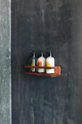 a shelf with four bottles on a wall at Naked Hotel Zipolite -Adults Only- in Zipolite