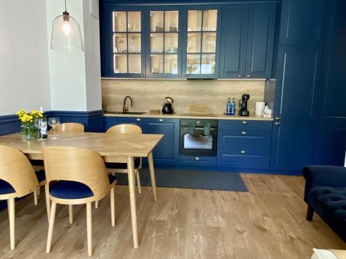 Apartament przy plaży Willa Redłowo في غدينيا: مطبخ مع دواليب زرقاء وطاولة وكراسي