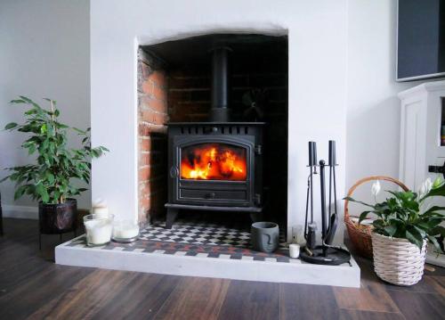 a stove in a living room with a brick fireplace at Victorian quirky farm cottage next to forest & close to beach in Woodbridge
