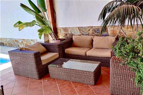 d'une terrasse avec des chaises en osier, un canapé et une table. dans l'établissement Casa Rural Los Olmos, à La Codosera