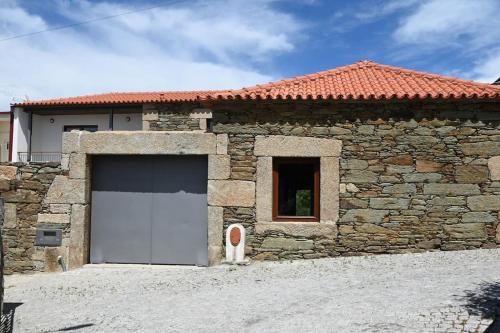a stone building with a white garage door at Casa de Trás-o-Muro in Vila Real