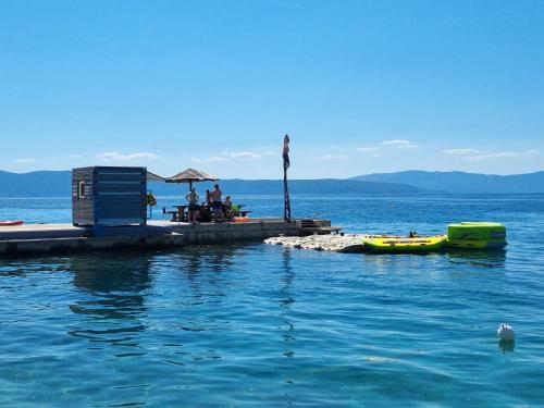 a group of people sitting on a dock in the water at Apartment Sol Dolcevita in Njivice