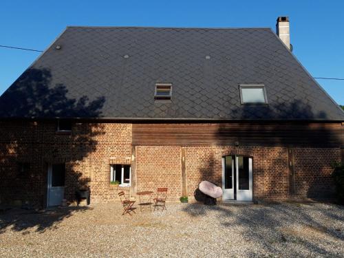a brick house with a black roof and chairs at Chambre d'hôtes chez CBL déco une pause charmante en normandie in Saint-Germain-des-Essourts