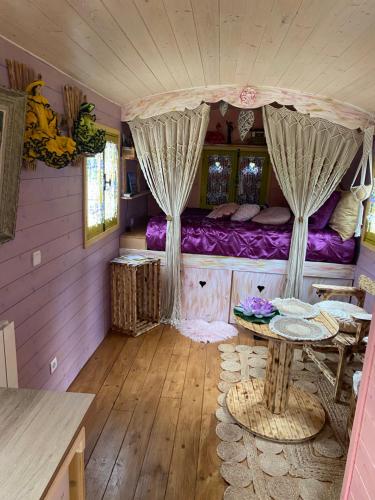 une pièce avec un lit et une table dedans dans l'établissement Roulotte pour une nuit en amoureux tout équipée.., à Noyelles-sur-Mer