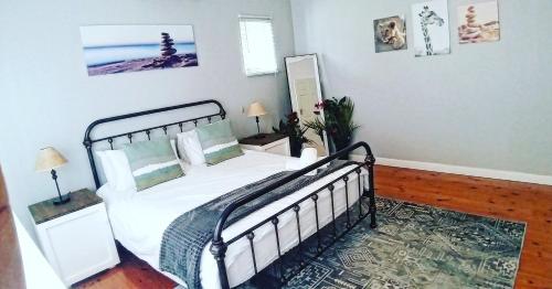 una camera da letto con letto, lenzuola e cuscini bianchi di Rose Holiday Home a Durban