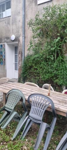 duas cadeiras de jardim sentadas ao lado de um banco de madeira em Le gite de la fontaine em Poyanne