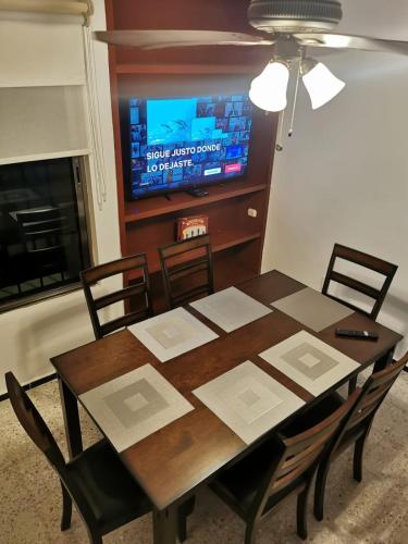 a dining room table with chairs and a television at Aparthotel Blue Star in Cancún