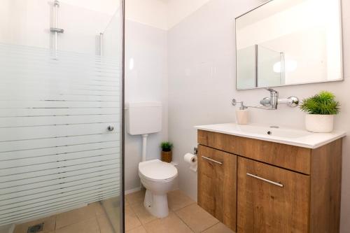 een badkamer met een toilet, een wastafel en een spiegel bij רז אירוח ברמה- in Qatzrin