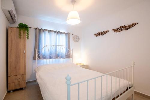 a white bedroom with a crib and a window at רז אירוח ברמה- in Qasrîne