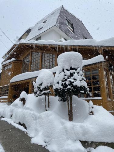 a building covered in snow with trees in front of it at Kihachikan South Nozawa Onsen in Nozawa Onsen