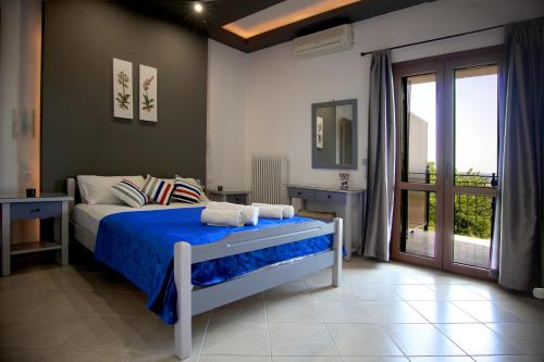 Schlafzimmer mit einem Bett mit blauer Bettwäsche und einem Fenster in der Unterkunft Seranides Boutique Hotel in Kato Gatzea