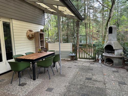een patio met een tafel en stoelen en een open haard bij Nunspeet Vakantiehuisje in Nunspeet