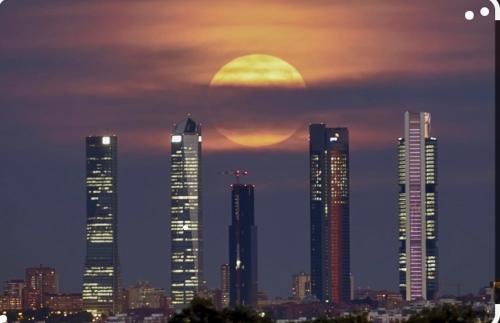 un grupo de edificios altos en una ciudad al atardecer en De Frente a 4 torres, Habitación con baño, en Madrid