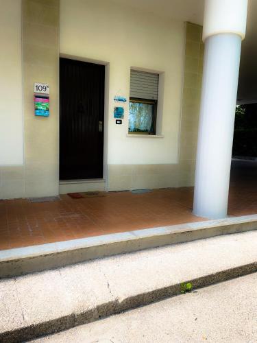 a building with a black door and two white columns at Casa Vacanze Cau de Mezo in Marina Julia