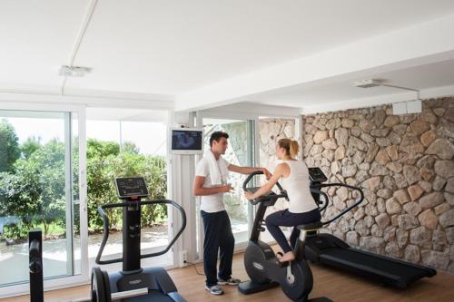 a man and a woman on an exercise bike in a gym at Baia Bianca Suites in Portoferraio