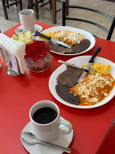 a red table with plates of food and a cup of coffee at Hotel Del Valle in El Naranjo
