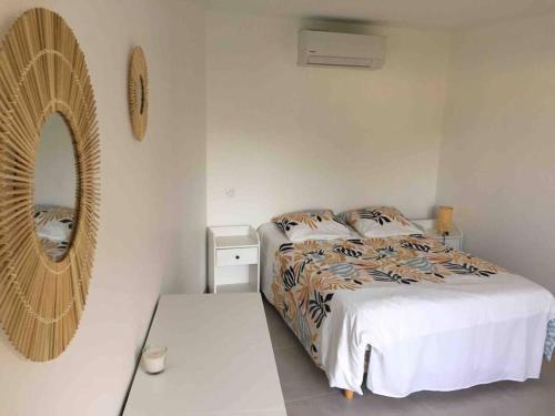 Habitación blanca con cama y espejo en Villa callinajo 1 T3 , 6 places Clim à 1 min de la plage, en Belgodère
