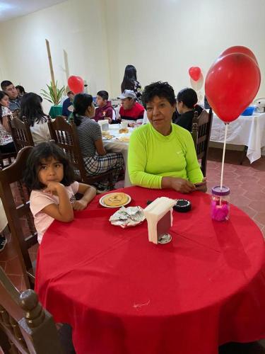 a woman and a little girl sitting at a red table at Hotel Del Valle in El Naranjo