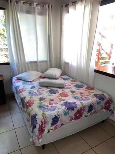 a bedroom with a bed with a floral bedspread and windows at Fosters West Bay Resort in West Bay