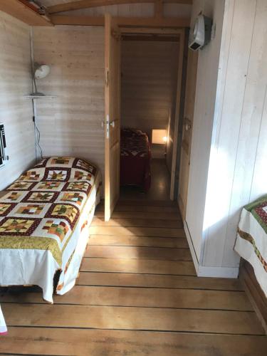 a bedroom with a bed in a wooden floor at Les roulottes de Moulin Rouge in Audelange