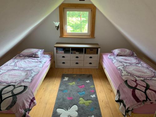 sypialnia na poddaszu z 2 łóżkami i oknem w obiekcie Domek wypoczynkowy Sosenkowo w mieście Suwałki