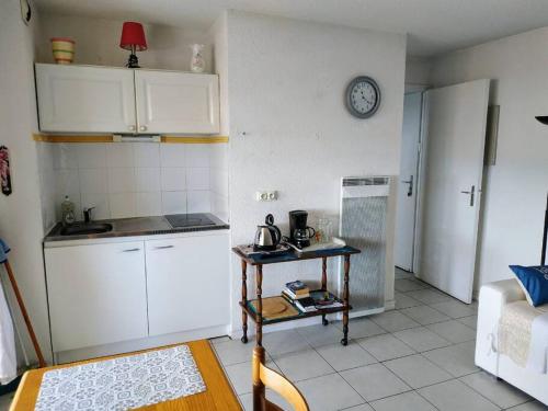 une petite cuisine avec une table et une horloge murale dans l'établissement Le Dali, Plage à 5 min parking, à La Seyne-sur-Mer