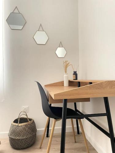 un bureau en bois avec une chaise noire à côté d'un mur dans l'établissement La Cornaline - Romans-sur-Isère, à Romans-sur-Isère