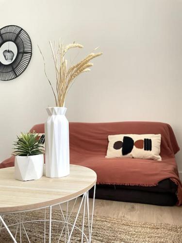 - un salon avec un canapé et une table avec un vase dans l'établissement La Cornaline - Romans-sur-Isère, à Romans-sur-Isère