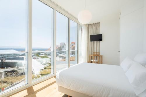 a bedroom with a white bed and a large window at Porto Real Hotel in Finisterre