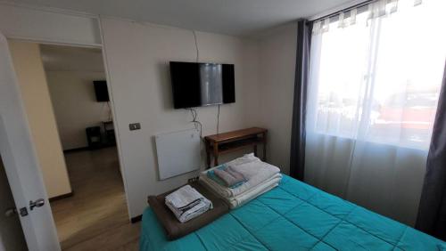 1 dormitorio con 1 cama, TV y ventana en Departamento a pasos del borde costero en condominio privado, en La Serena