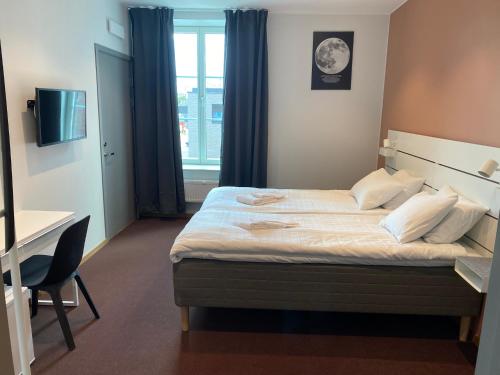 Schlafzimmer mit einem Bett, einem Schreibtisch und einem Fenster in der Unterkunft Ahlgrens Hotell Bed & Breakfast in Gävle