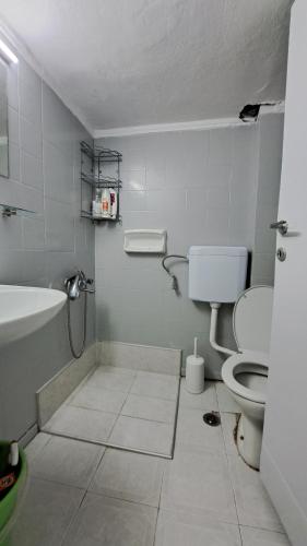 a white bathroom with a toilet and a sink at Beachfront apartment 10m from the beach in Paralia Dionysiou