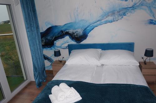 a bedroom with a bed with a painting on the wall at Villa Laguna Blue in Swarzewo