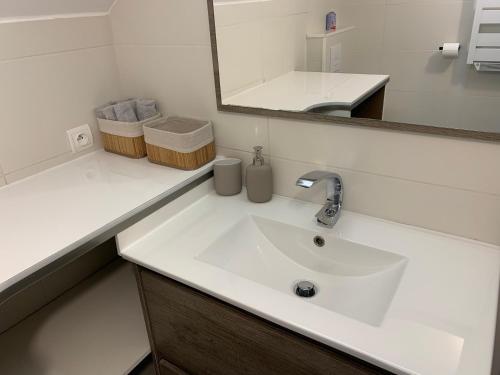 Baño blanco con lavabo y espejo en Coquet appartement aux pieds des montagnes, en Scionzier