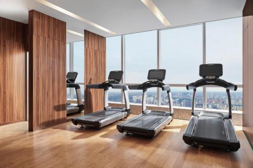 a gym with a row of treadles in a room with windows at InterContinental Hanoi Landmark72 by IHG in Hanoi