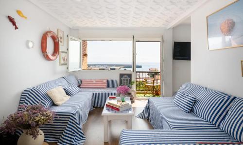 ein Wohnzimmer mit blau und weiß gestreiften Sofas in der Unterkunft La Casa del Gallo in Luanco