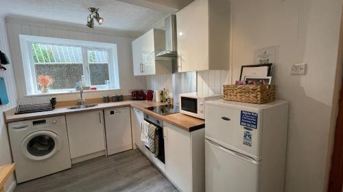 a kitchen with a washer and dryer and a sink at Stylish Garden Flat Near Loch Ness - Perfect Nessie Stopover in Drumnadrochit