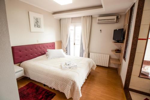 um quarto com uma cama grande e uma cabeceira vermelha em Hotel Prata Villaggio em Nova Prata