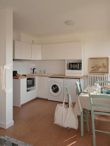 a kitchen with white cabinets and a table with a bag at L'heure Bleue - Meublé de tourisme 3 étoiles in Royat