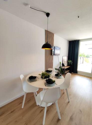 a white dining room table with white chairs and a lamp at Sauna, Pools mit XXL-Terasse oder Kinderkino in Sankt Englmar