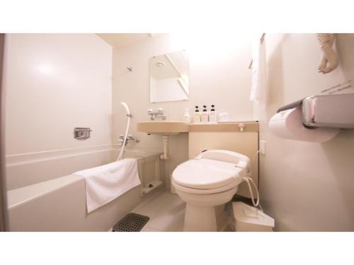 La salle de bains blanche est pourvue de toilettes et d'une baignoire. dans l'établissement Hotel Satsukien - Vacation STAY 75958v, à Kanoya