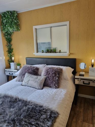 sypialnia z łóżkiem z poduszkami futerkowymi i oknem w obiekcie Firbog Nook w mieście Antrim