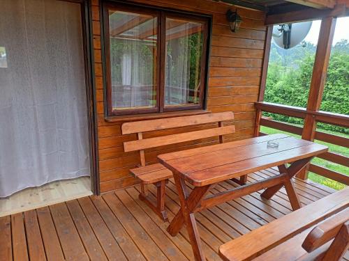 a wooden porch with a table and benches on it at Jaś Roztocze in Nielisz