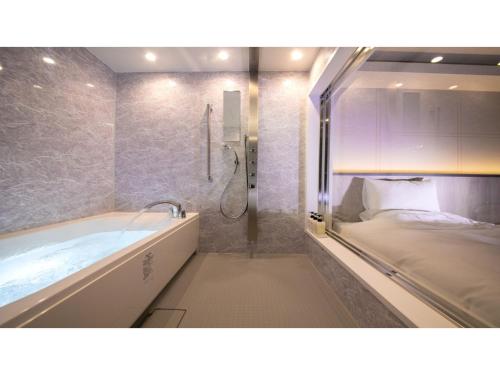 a bathroom with a tub and a bed in it at Hotel Satsukien - Vacation STAY 75962v in Kanoya