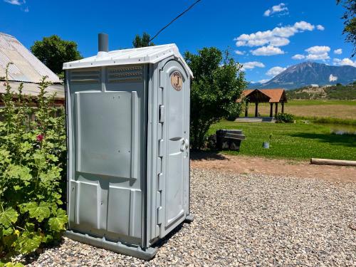 a outhouse sitting on the gravel in a garden at Violet Cottage at Zenzen Gardens in Paonia