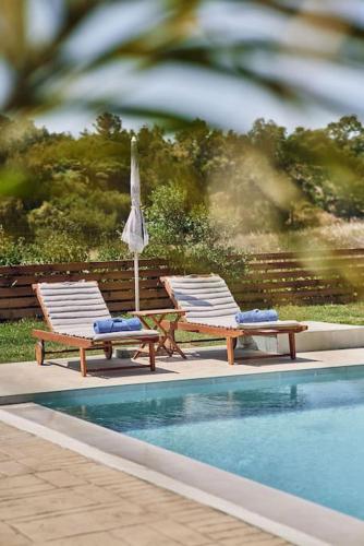 two chairs and an umbrella next to a swimming pool at Villa Arianna, close to the beach! in Kalamaki