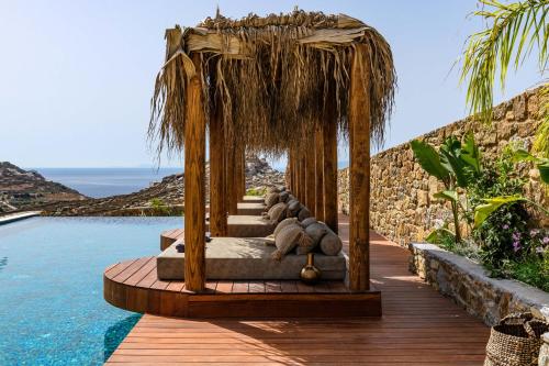 Charisma Hotel and Wellness Suites في Plintri: سرير مع وسائد على سطح خشبي بجوار حمام سباحة