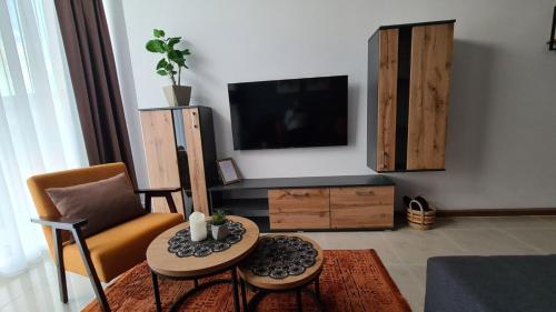 a living room with a tv and a chair and a table at Apartman Orange in Bugojno